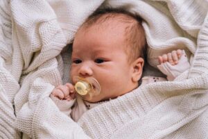 Bebê deitado com chupeta na boca