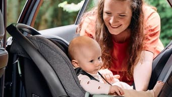 Mulher colocando bebê na cadeirinha no carro