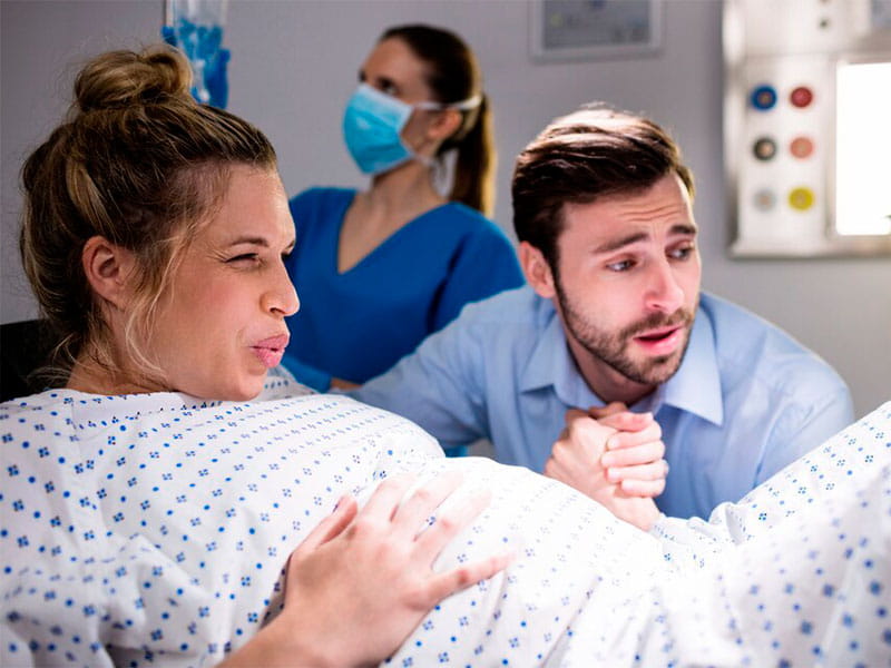 mulher no hospital de avental em trabalho de parto de mãos dadas com um homem
