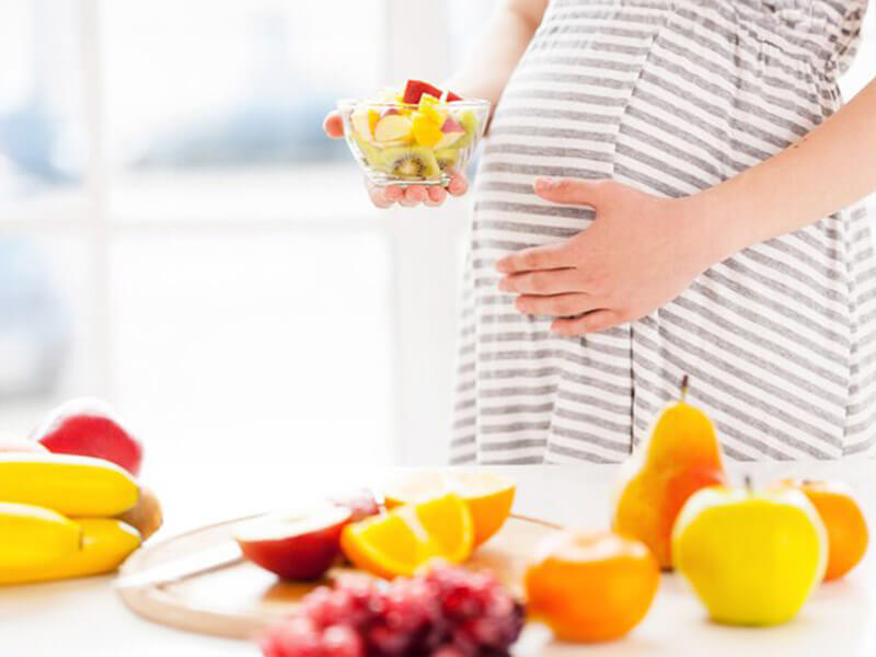 Mulher gravida comendo frutas