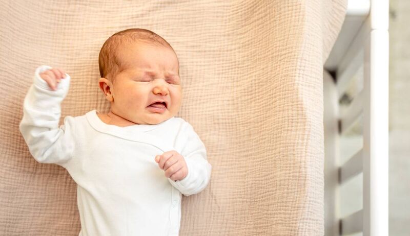 Bebê acordando e fazendo careta em cama