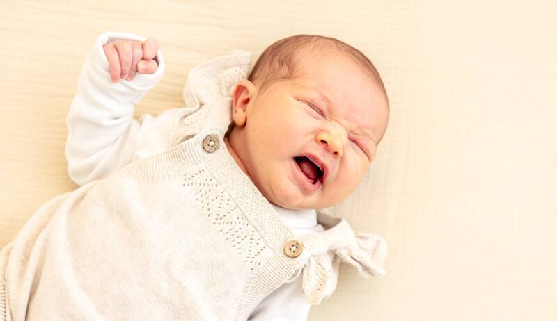 Bebê sorrindo em roupa clara, expressão fofa