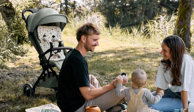Família relaxando ao ar livre com carrinho de bebê