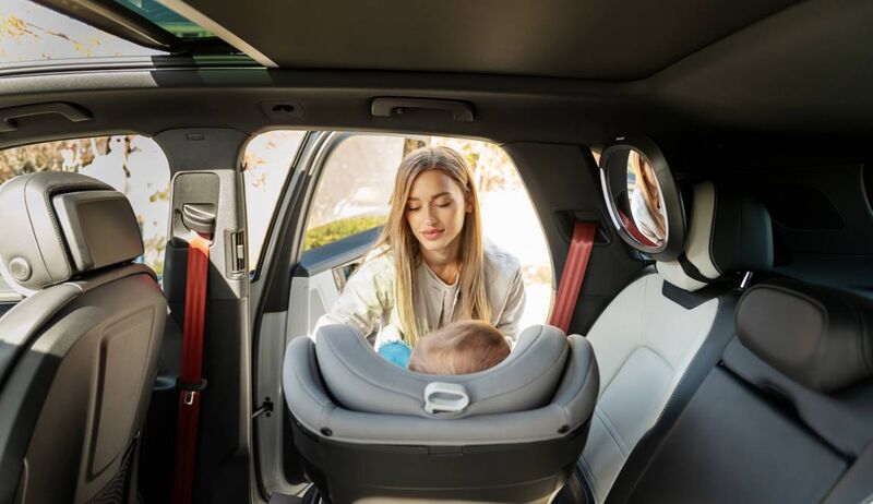 Mãe colocando criança em cadeirinha no carro